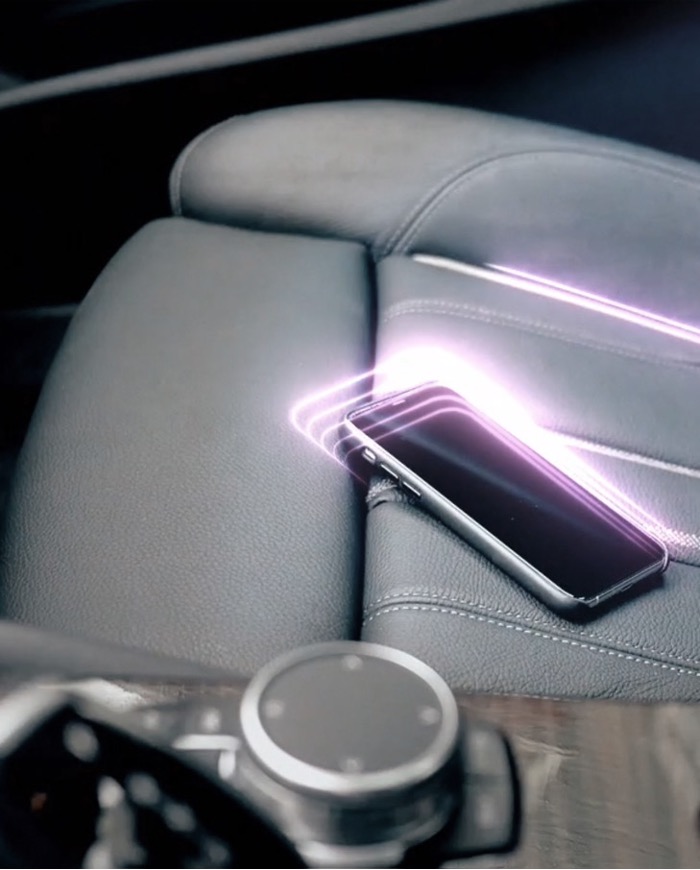 BMW concept render of a phone resting on the rear armrest with a glowing visual outline detecting it.