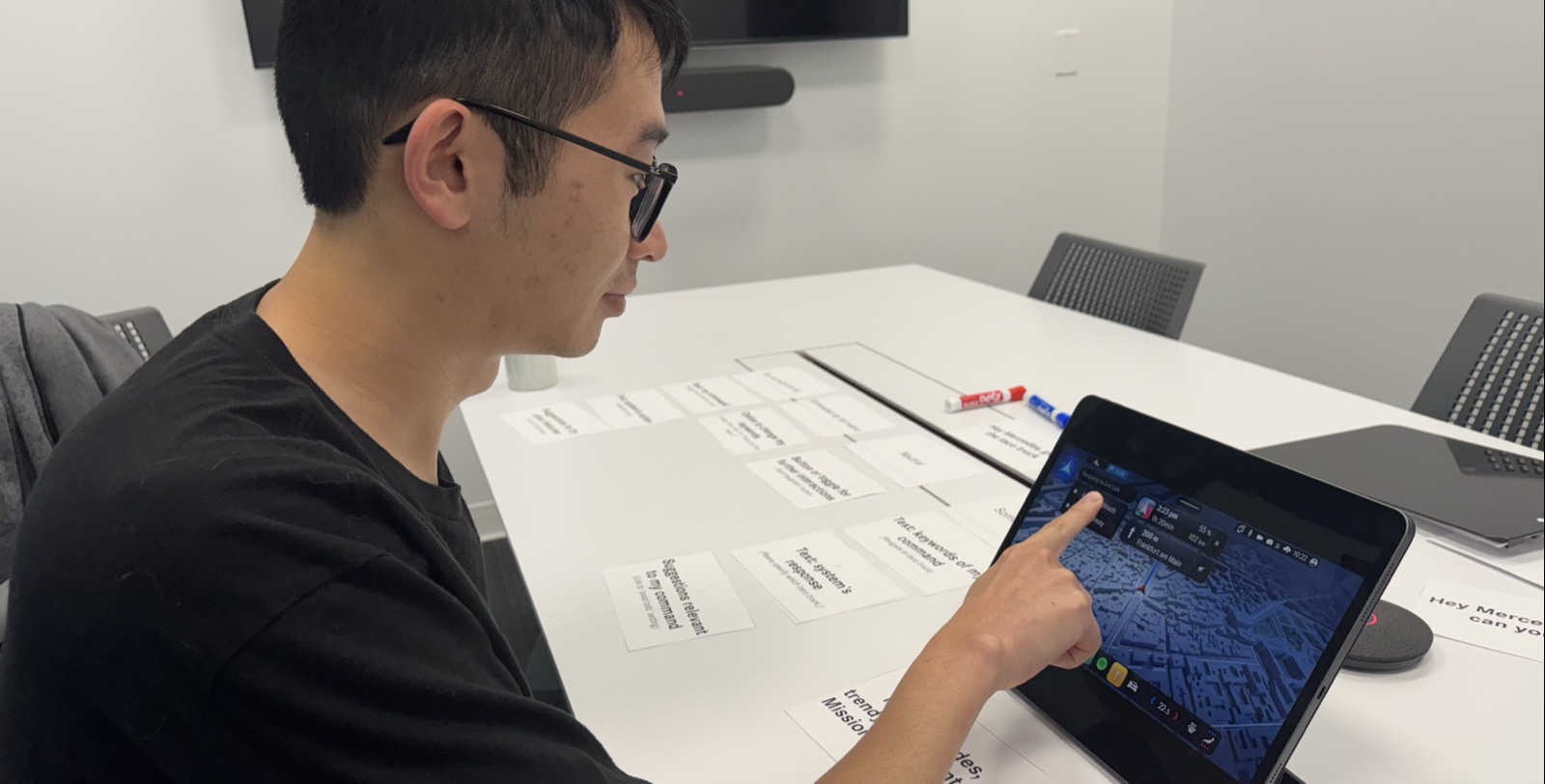 Subject interacting with a Figma click-through on a tablet, with note cards spread on the table.